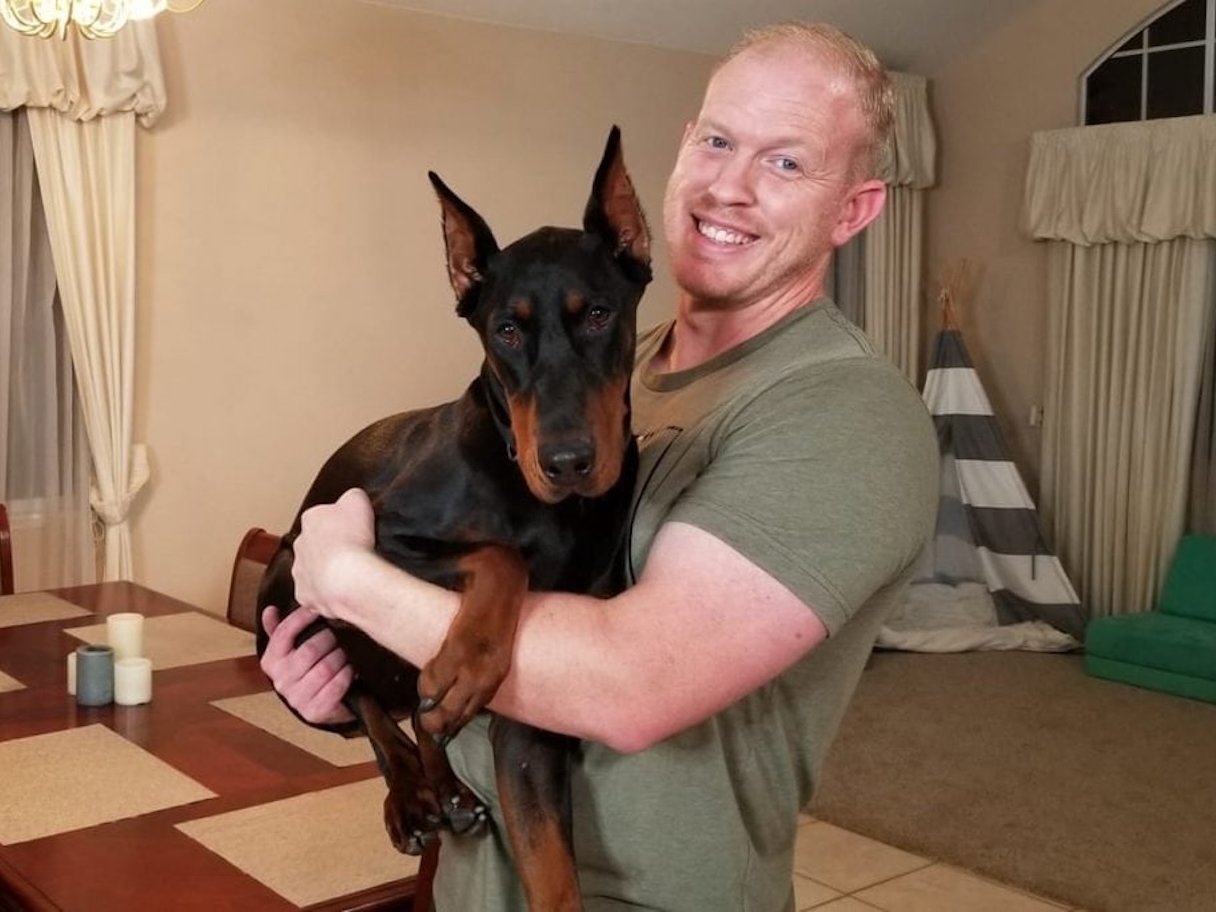 Un homme fait un câlin à son doberman