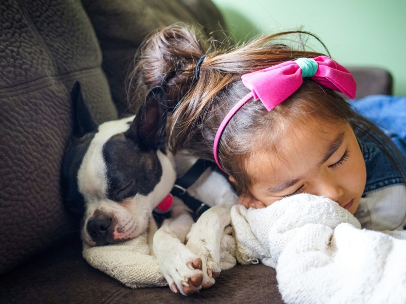 une fille qui dort avec un chien sur un canapé
