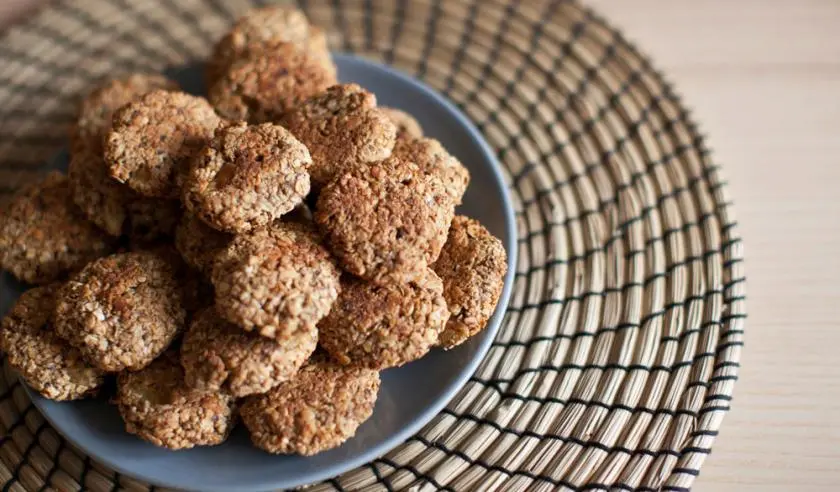 Assiette remplie de biscuits maison pour chien, faits à base d'ingrédients naturels, disposée sur un set de table en rotin